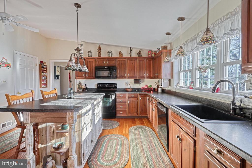 Kitchen with warm wood cabinets, a large island, dark counters, and windows above the sink.