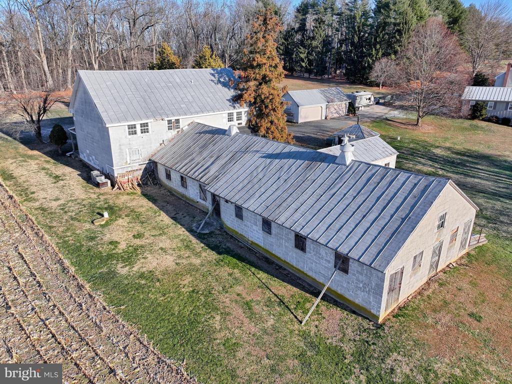 Aerial view of several metal-roofed outbuildings surrounded by grass and mature trees.