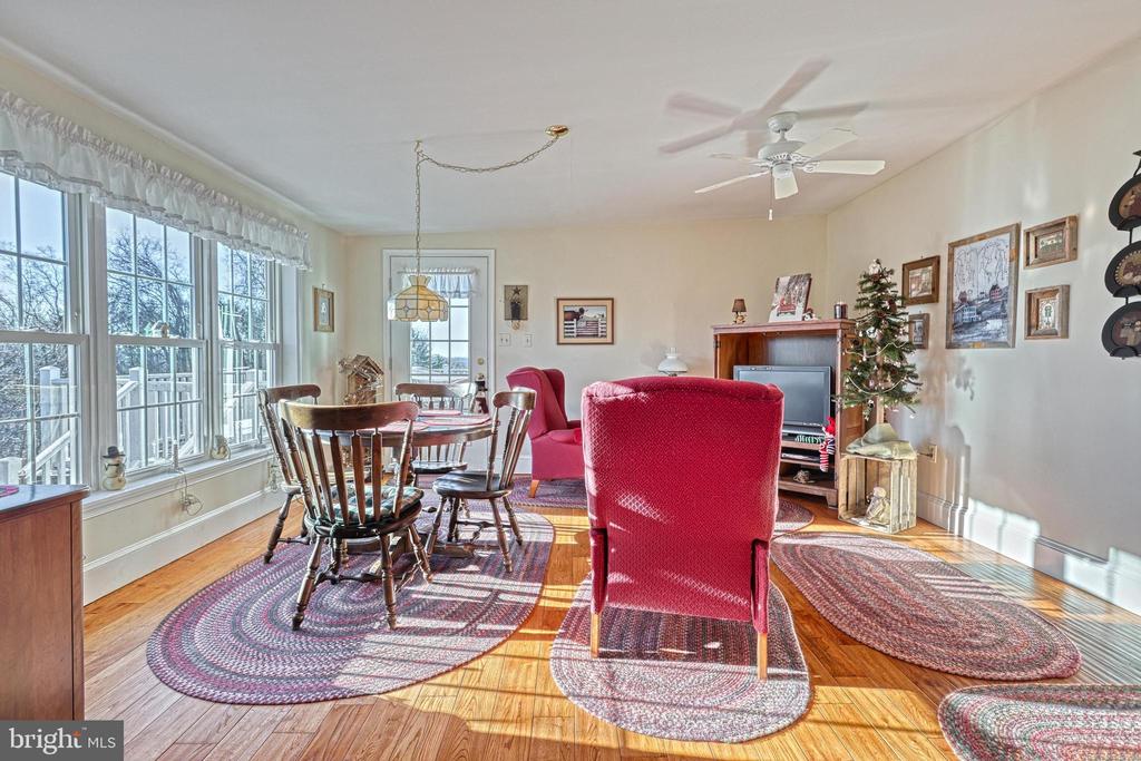 Living and dining area with red chairs, hardwood floors, large windows, and a decorated Christmas tree.