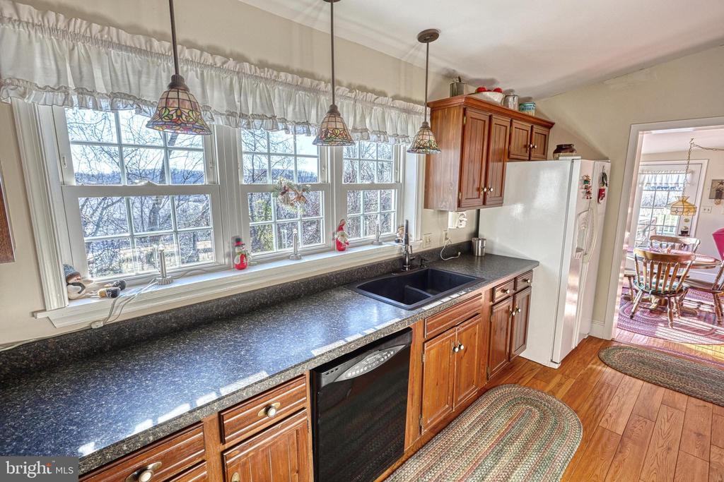 Kitchen with dark granite counters, a window-side sink, and warm wood cabinets.