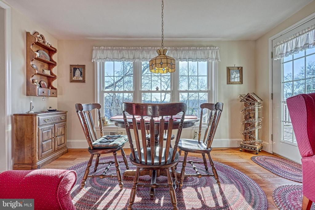 Dining room with a round wooden table, spindle-back chairs, bay windows, and hardwood floors.
