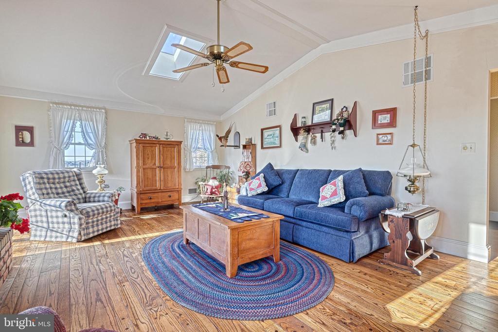 Living room with blue sofa, plaid armchair, hardwood floors, and a skylight.