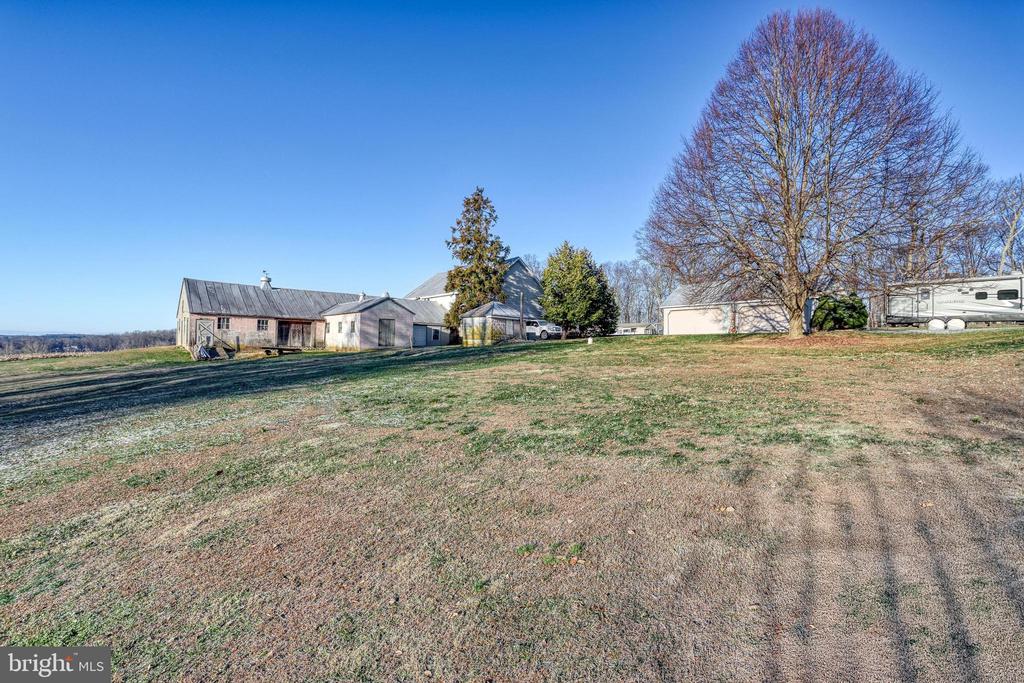 Property grounds with several outbuildings, a broad grassy yard, and a large leafless tree.