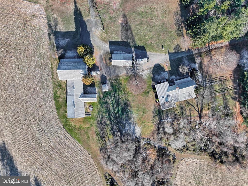 Aerial view of a rural property with several buildings, a driveway, and surrounding fields.