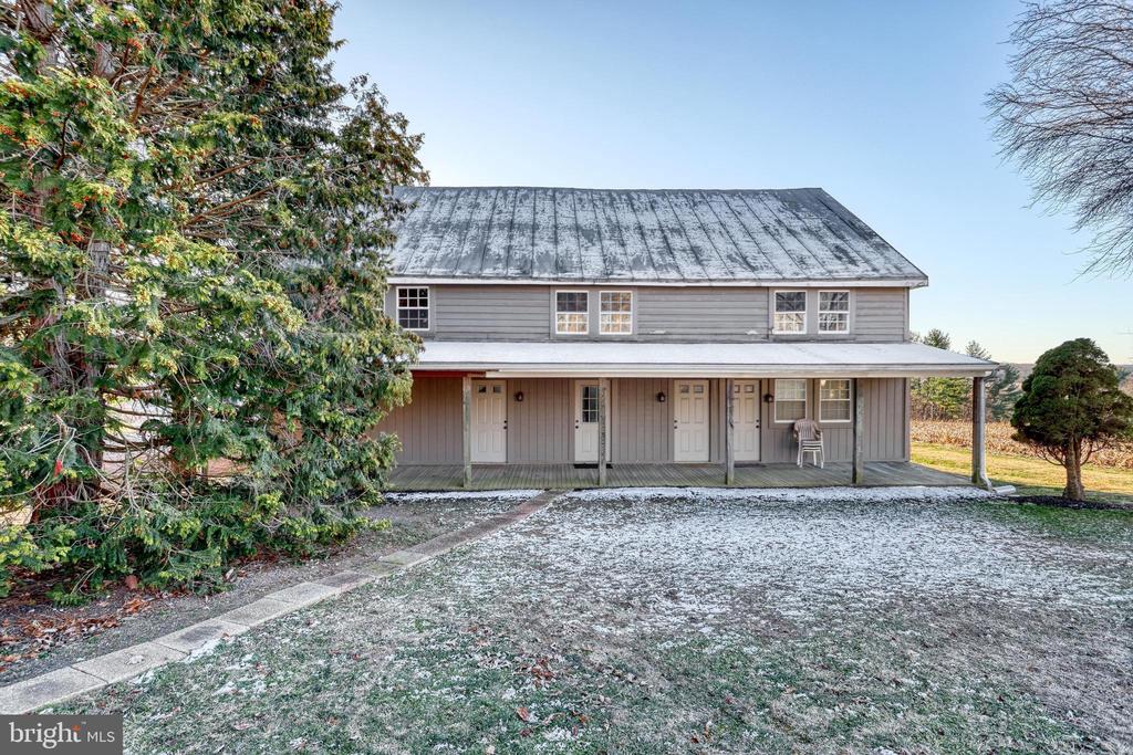 Gray two-story house with a covered porch and metal roof, lightly dusted with snow.