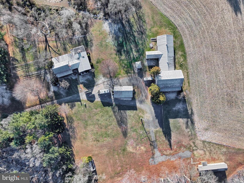 Aerial view of a rural property with several outbuildings beside a cultivated field.