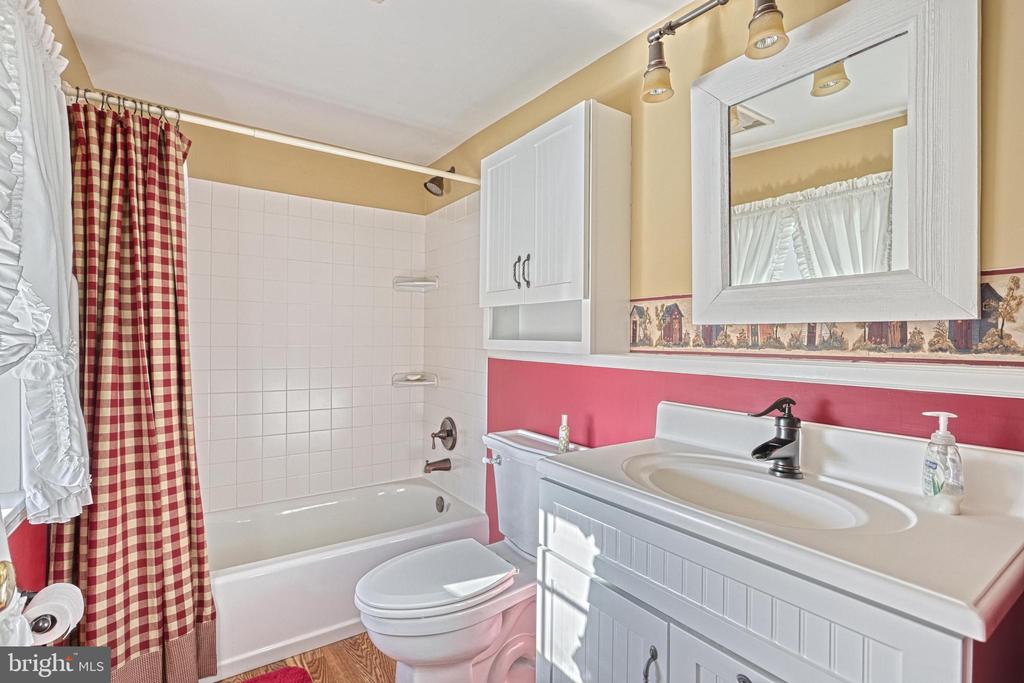 Bathroom with a checked shower curtain, white vanity, framed mirror, and pink walls.