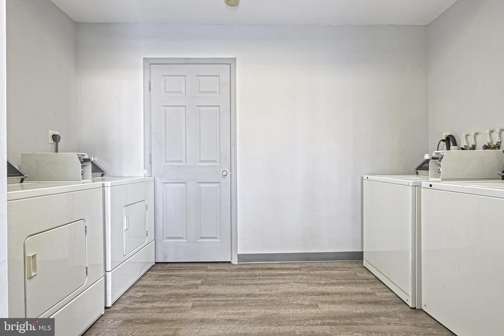 Laundry room with white washer and dryer units along both sides and wood-look flooring.