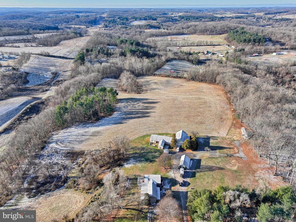 Rural property with expansive fields, wooded boundaries, and several buildings.