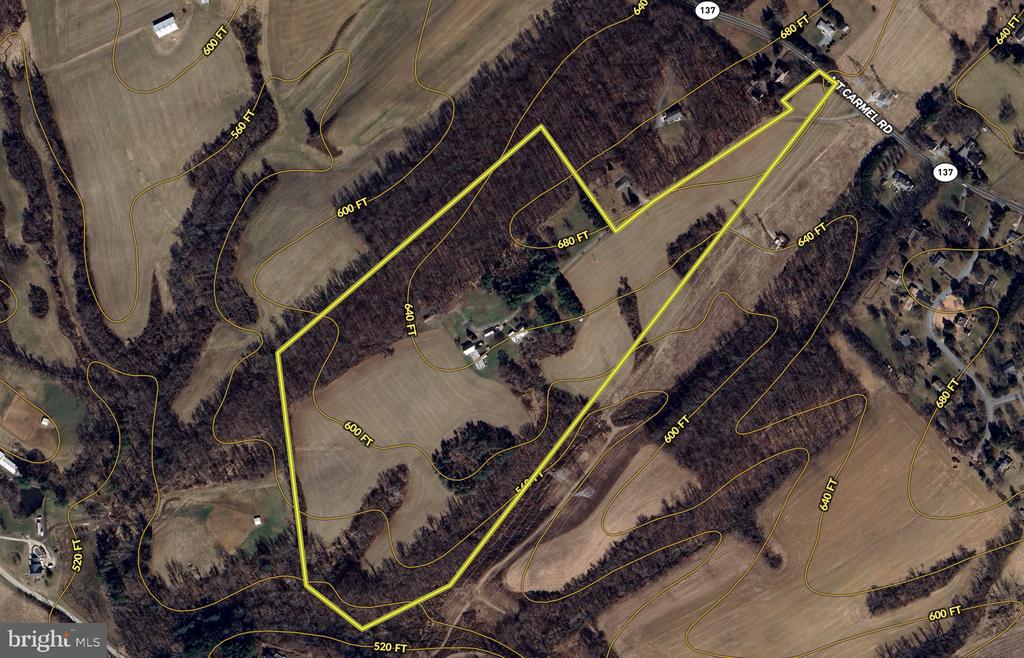 Aerial view of rural property outlined in yellow, with open fields, wooded areas, buildings, and elevation contours.