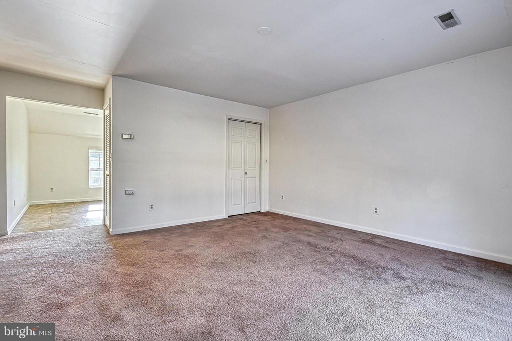 Vacant carpeted room with a double-door closet and an adjoining tiled room.