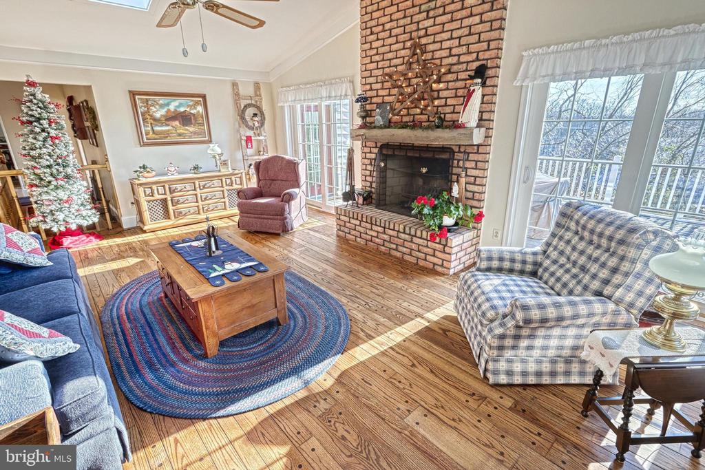 Living room with a brick fireplace, hardwood floors, and a decorated Christmas tree.