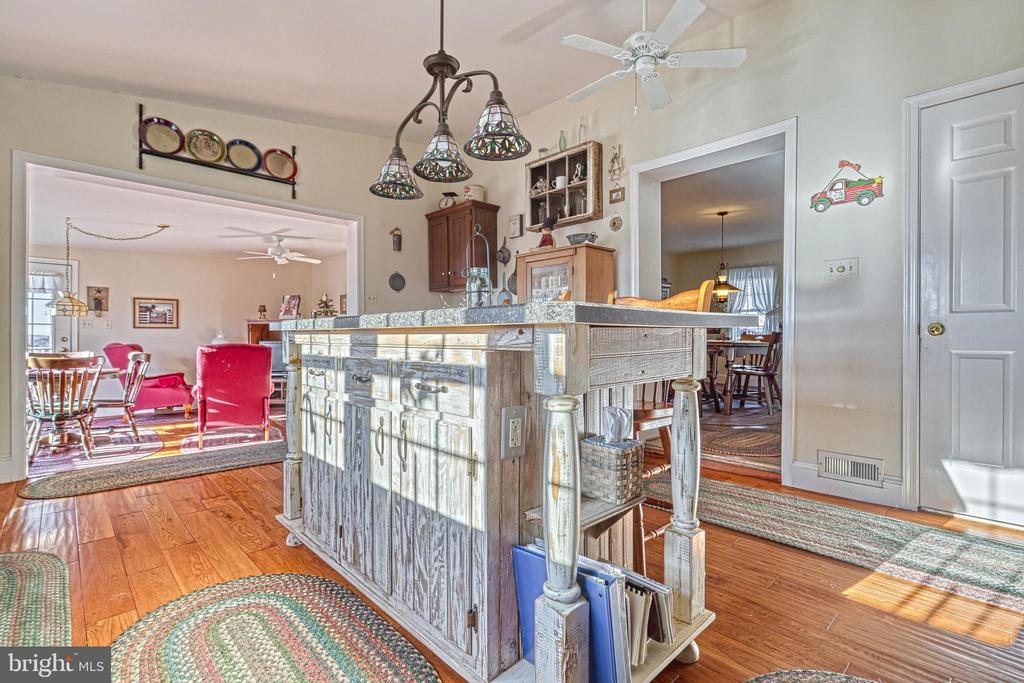 Kitchen with a large distressed-wood island, stone countertop, and adjoining living and dining areas.