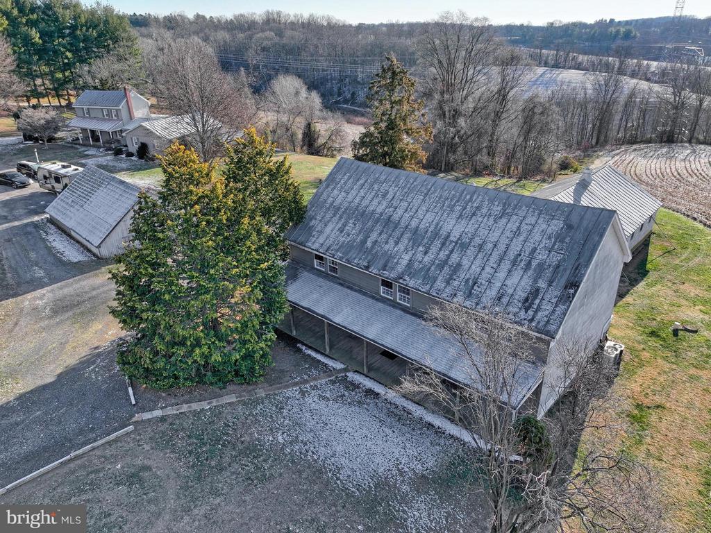 Aerial view of a large gray-roofed property building, with a smaller outbuilding and leafless trees.