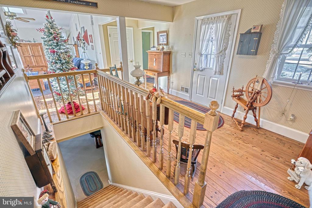 Upstairs landing and staircase with a wooden balustrade, hardwood floors, and a spinning wheel.