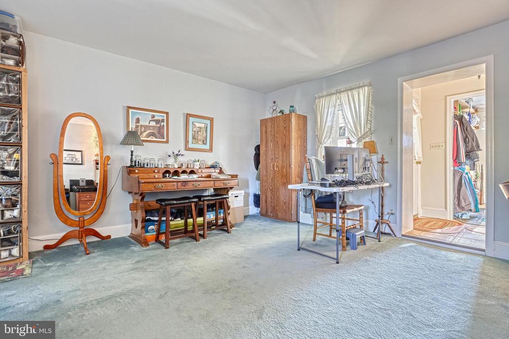 Bedroom with carpet, a wooden vanity and wardrobe, and a desk beneath a curtained window.