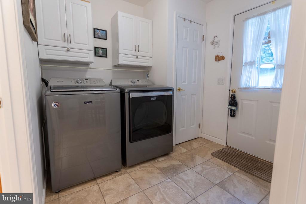 Laundry room with a side-by-side washer and dryer beneath white cabinets.