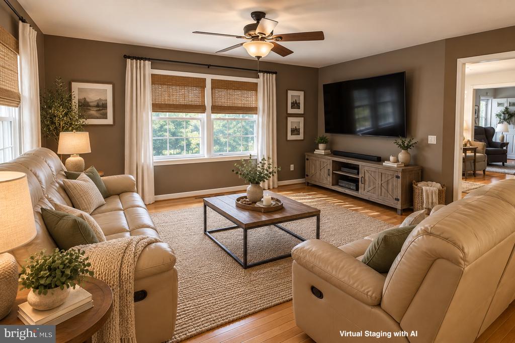 Virtually staged living room with tan leather sofas, woven rug, and a wall-mounted television.