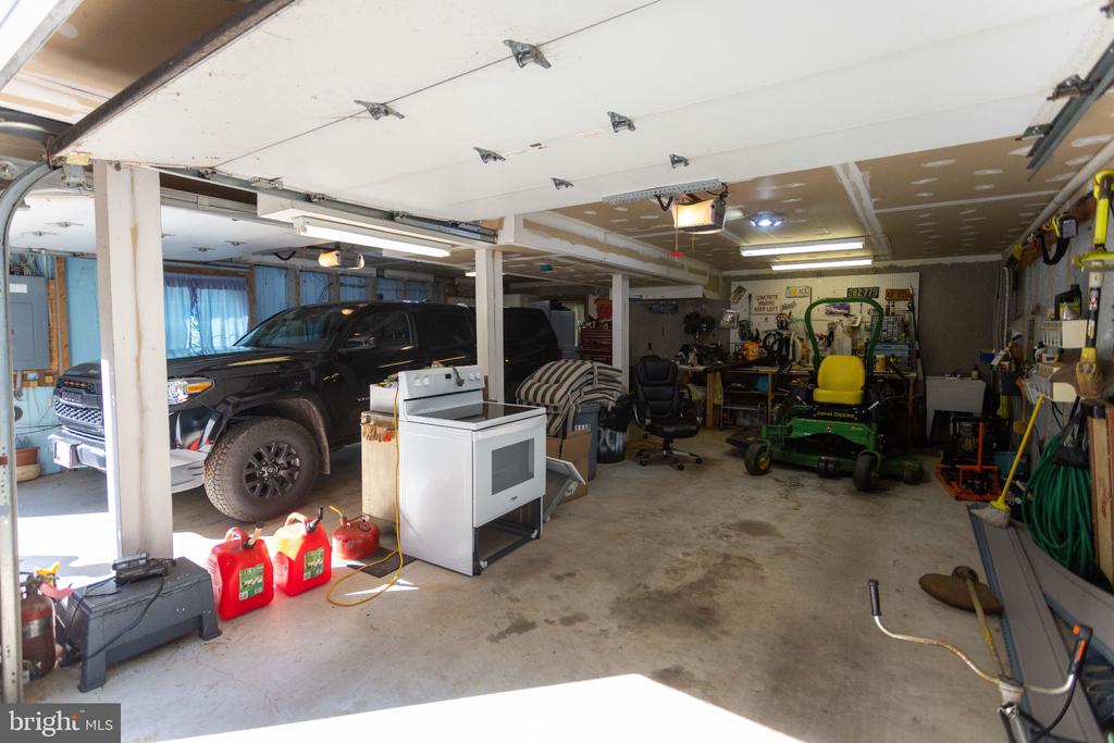Garage with a pickup truck, lawn tractor, workbench, and tools.