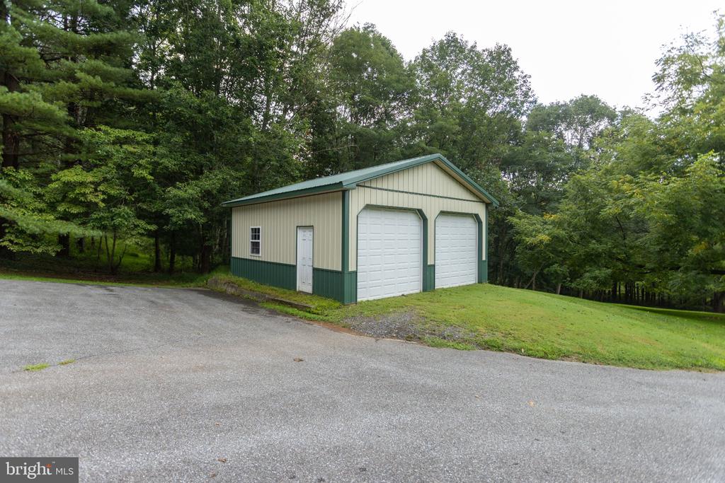 Detached cream garage with green trim, two overhead doors, and a paved driveway.