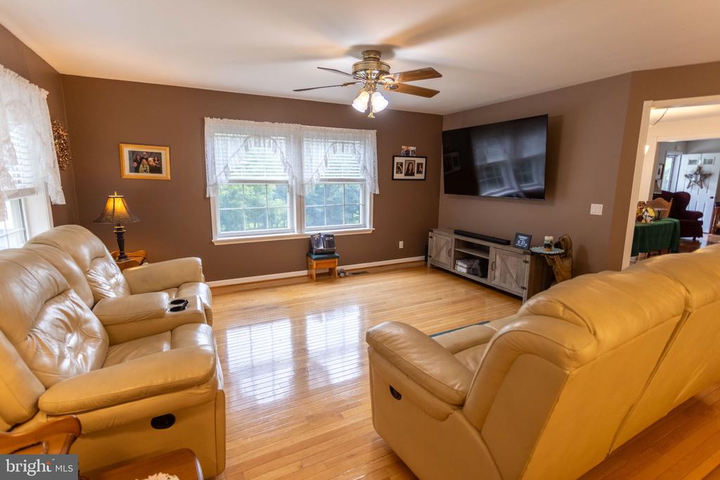 Living room with tan leather recliners, hardwood floors, and a wall-mounted television.