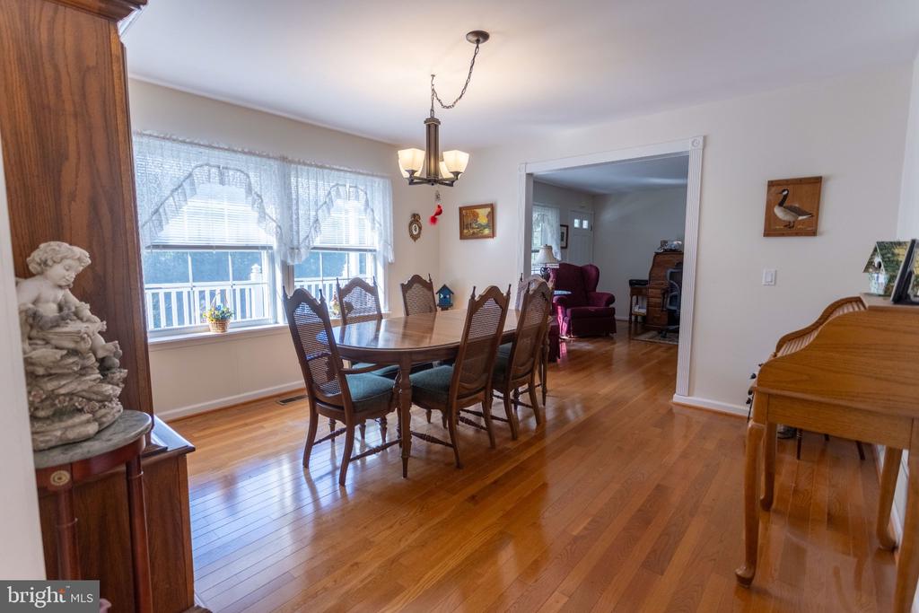 Dining room with a wooden table, hardwood floors, large windows, and a chandelier.