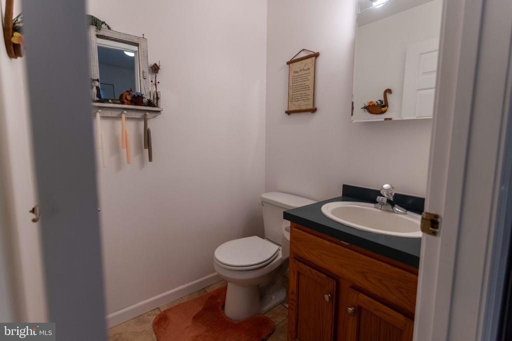 Bathroom with a wood vanity, dark countertop, oval sink, and orange bath mat.