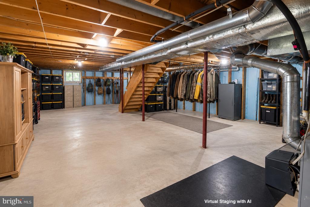 Finished basement with exposed ductwork, storage shelves, hanging coats, and a wooden staircase.