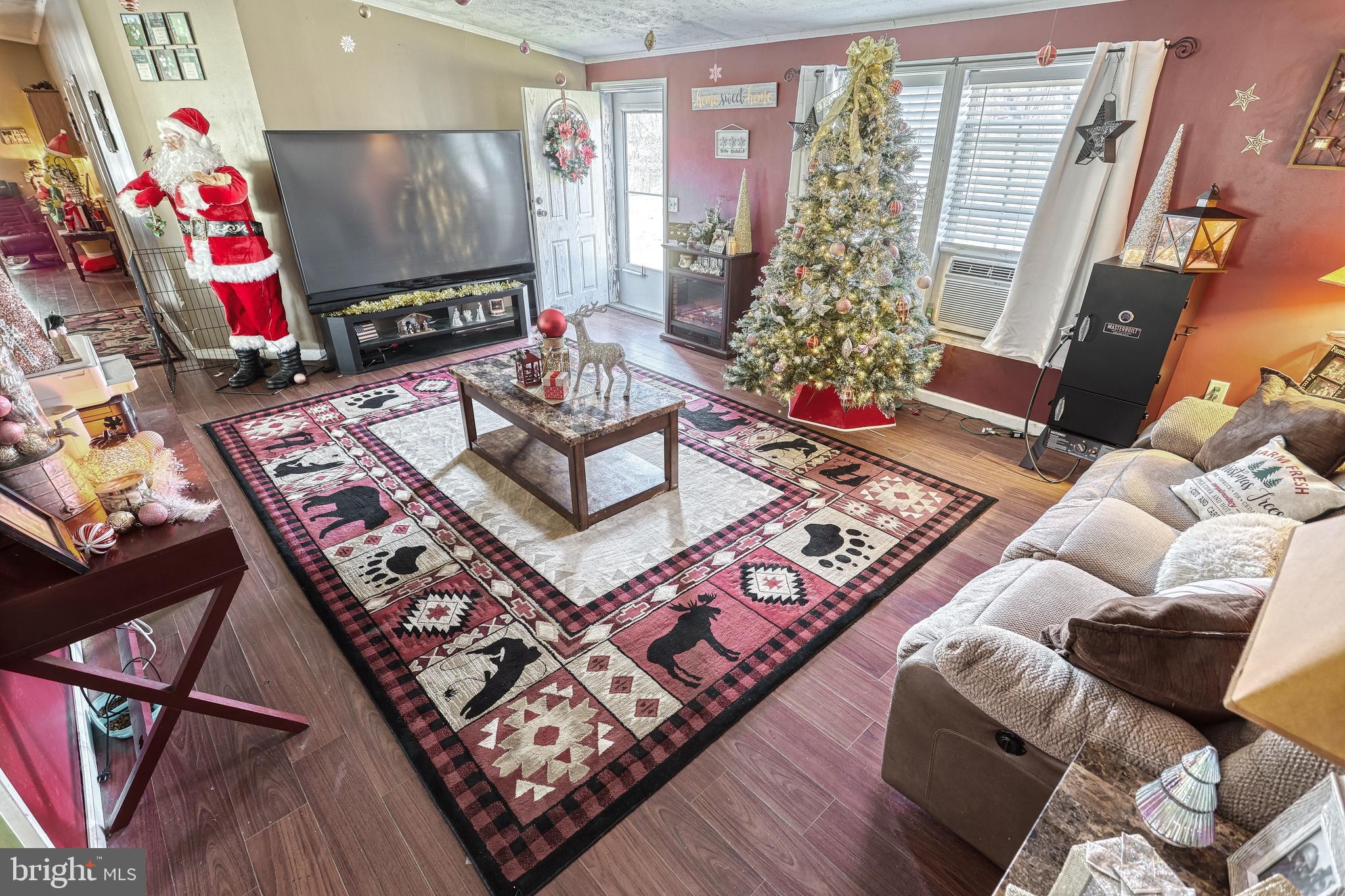 Living room with a decorated Christmas tree, Santa figure, large patterned rug, and sectional sofa.