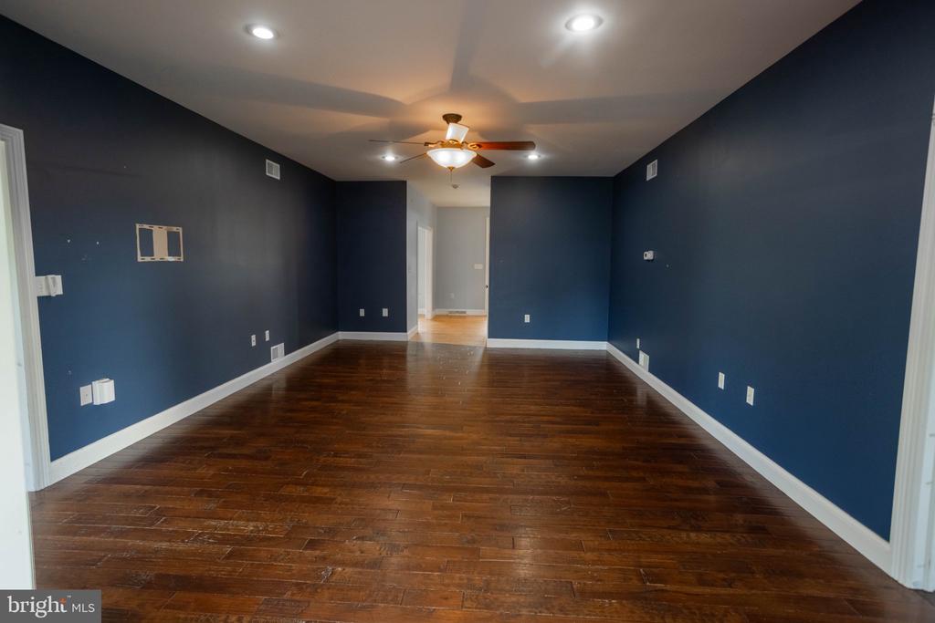 Empty room with dark blue walls, hardwood floors, and a ceiling fan.