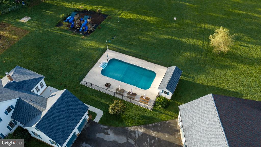 Aerial view of a home with a fenced swimming pool and children’s play area.