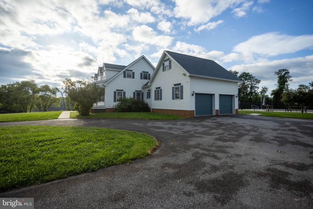 White-sided home with a two-car garage, broad driveway, and green lawn.
