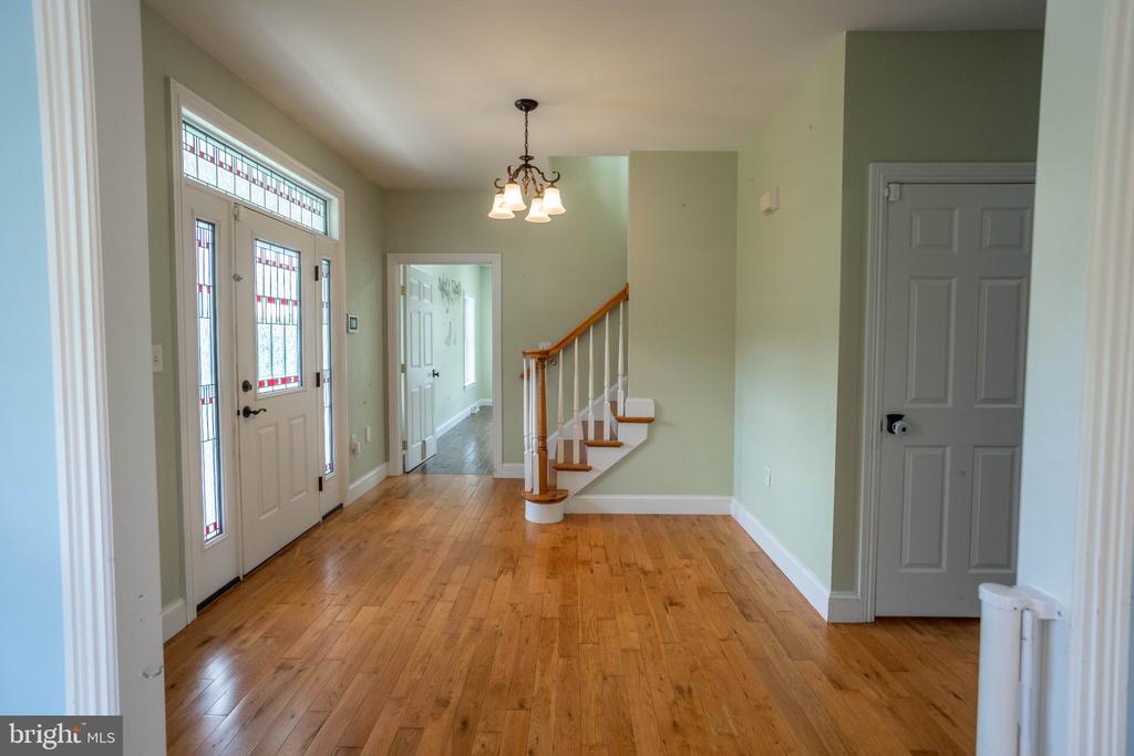 Entry hall with hardwood floors, decorative glass front door, small staircase, and chandelier.