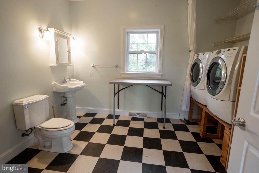 Bathroom and laundry room with a pedestal sink, side-by-side washer and dryer, and checkered floor.