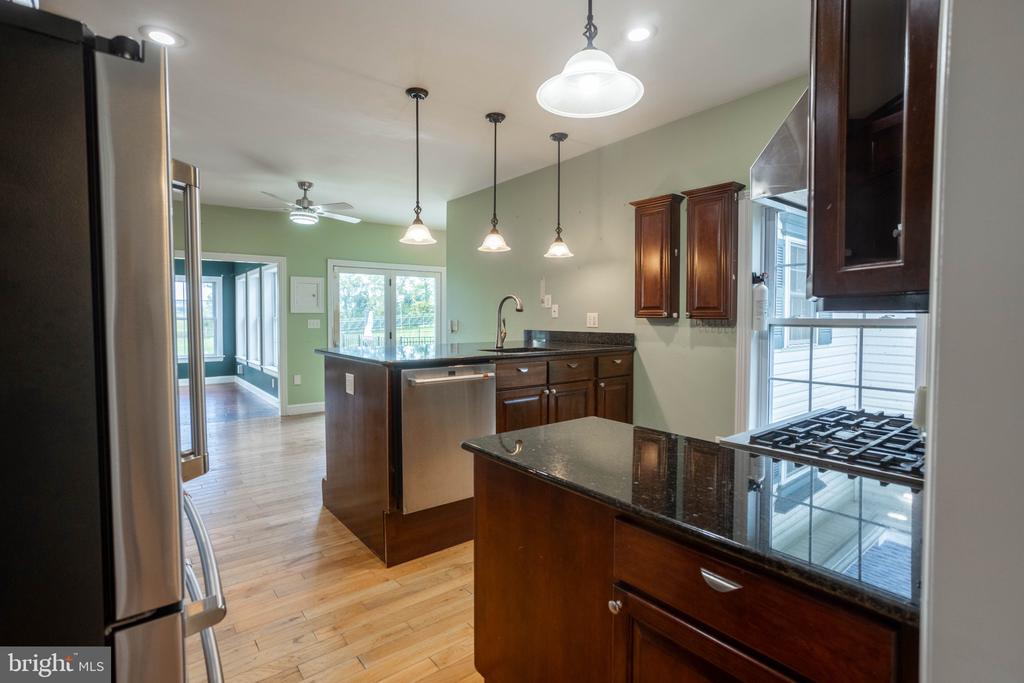 Kitchen with dark wood cabinetry, granite counters, stainless steel appliances, and an island.
