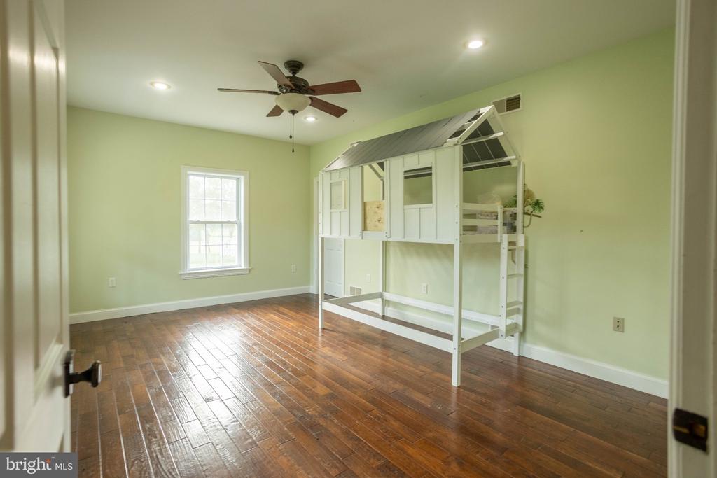 Bedroom with a white house-shaped loft bed frame, hardwood floors, and a ceiling fan.