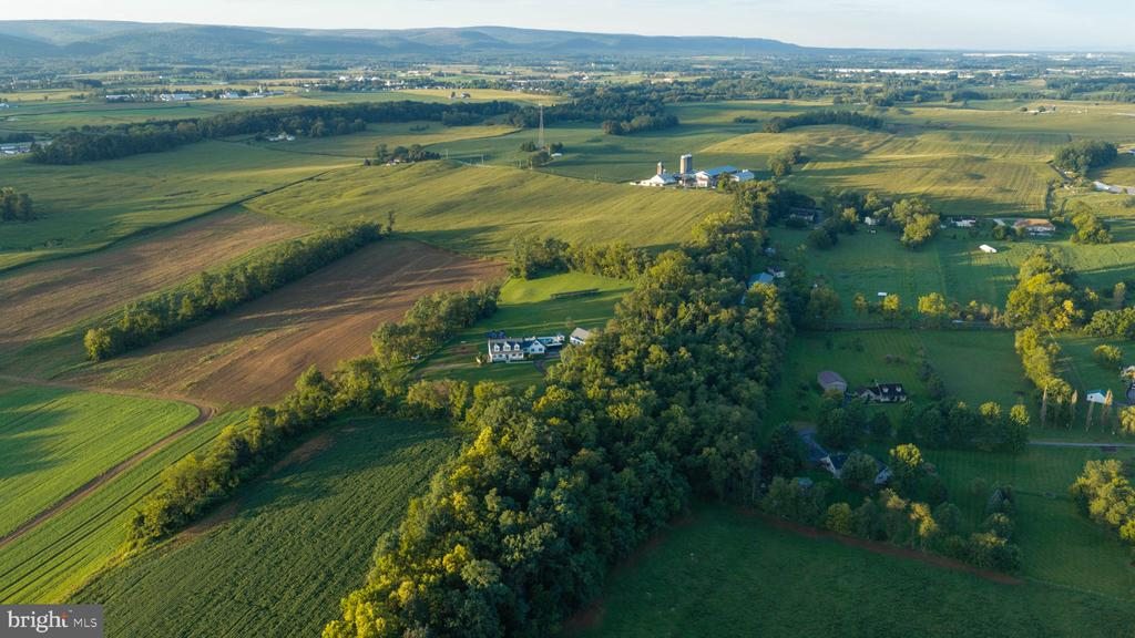 Aerial view of a rural home amid wooded land and expansive farmland.