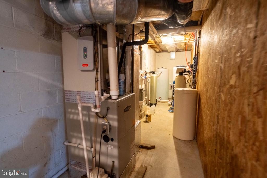 Basement utility room with a furnace, water heaters, and exposed ductwork.