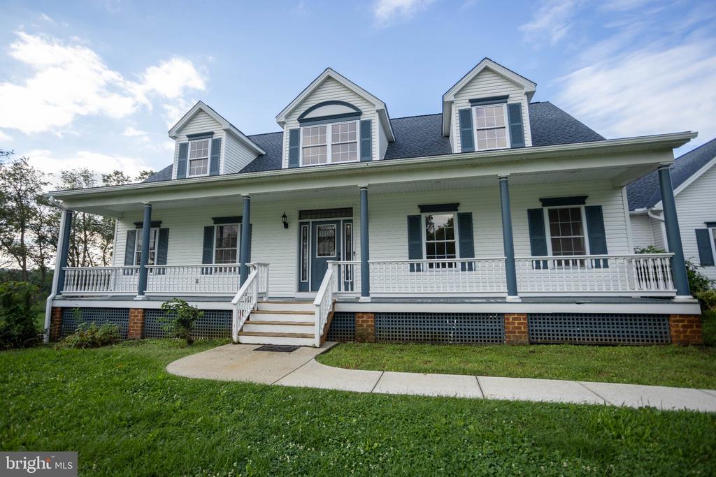 White two-story house with three dormers and a long covered front porch.