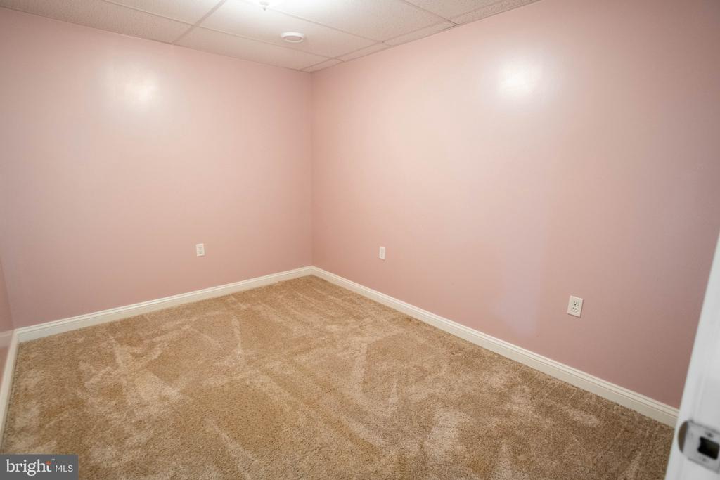 Empty room with pink walls, beige carpet, and a suspended ceiling.