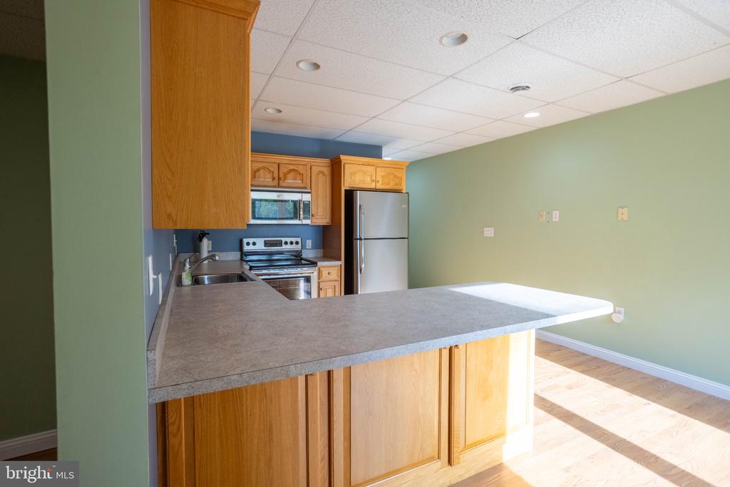Kitchen with a wide gray peninsula, wood cabinets, and stainless steel appliances.