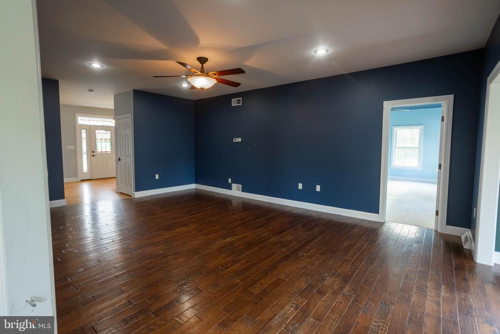 Empty living room with dark hardwood floors, navy walls, and a ceiling fan.