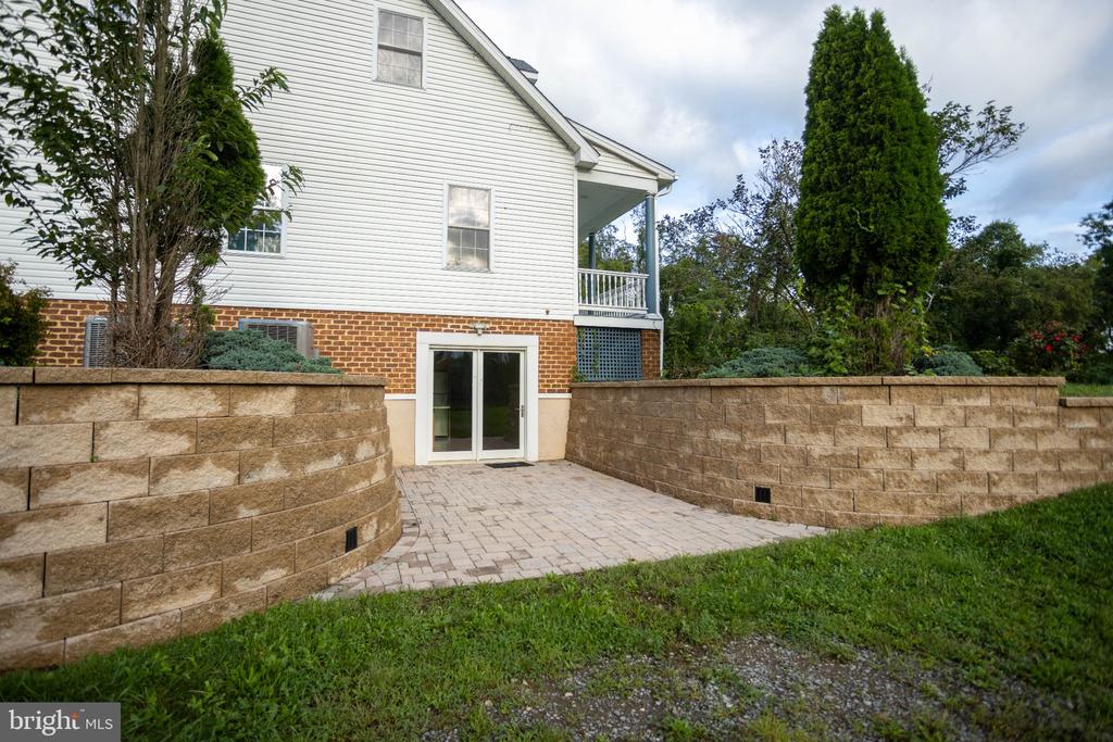 Home exterior with a paved patio, sliding glass door, and curved block retaining walls.