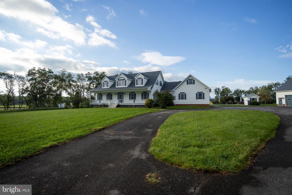 House with a wraparound porch and dormer windows beside a curved driveway.