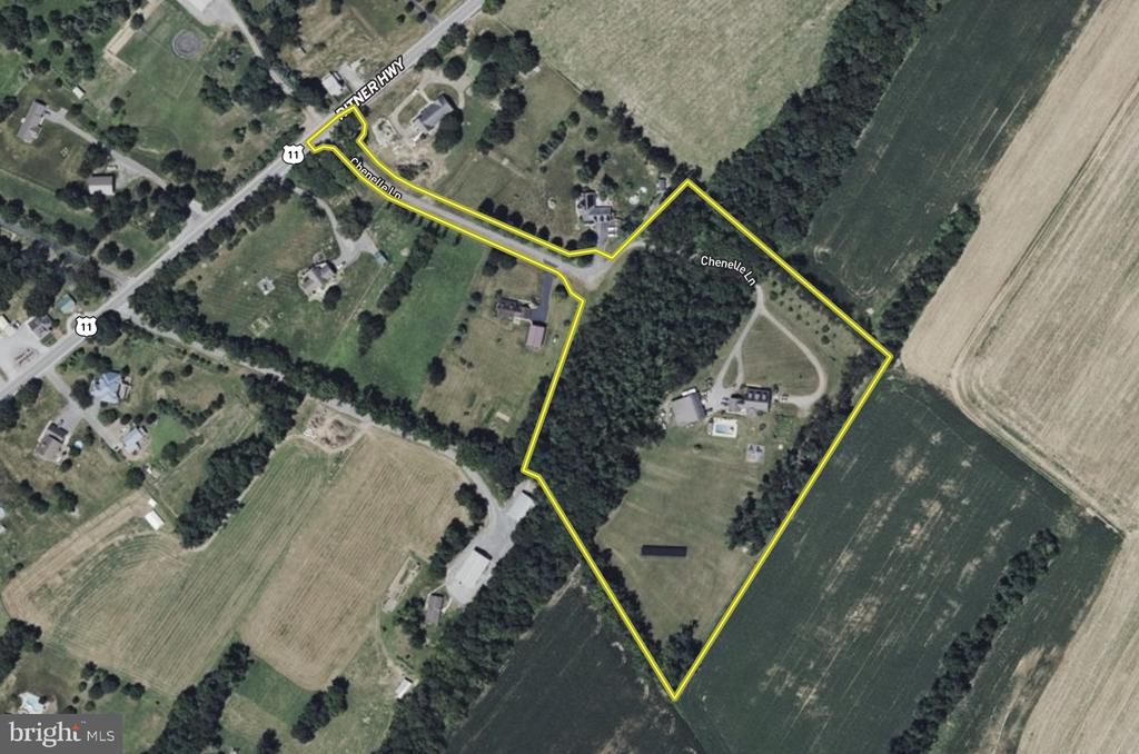 Aerial view of a yellow-outlined property with fields, woods, and buildings.