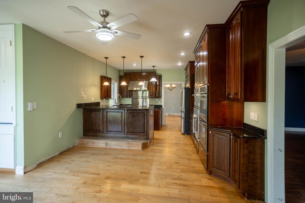 Kitchen with a dark wood island, stainless steel appliances, and light wood floors.