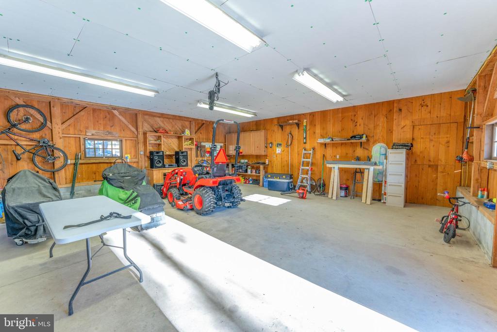 Wood-paneled garage with lawn tractors, bicycles, tools, and a concrete floor.