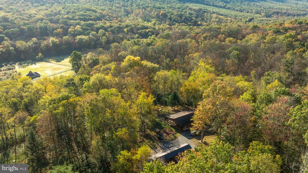 Aerial view of a home surrounded by autumn woods and rolling hills.