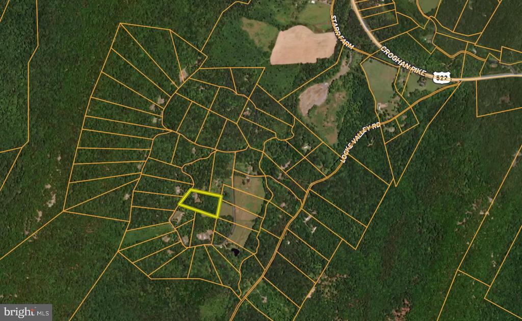 Aerial view of a wooded parcel outlined in yellow among surrounding land parcels.