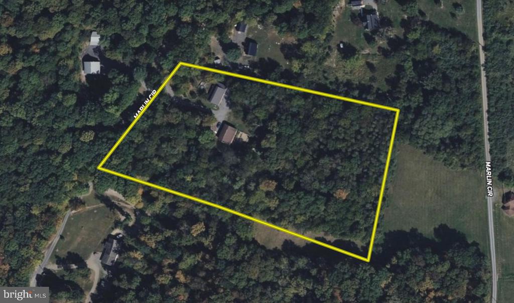 A wooded parcel outlined in yellow, with two buildings among the trees beside Marlin Circle.